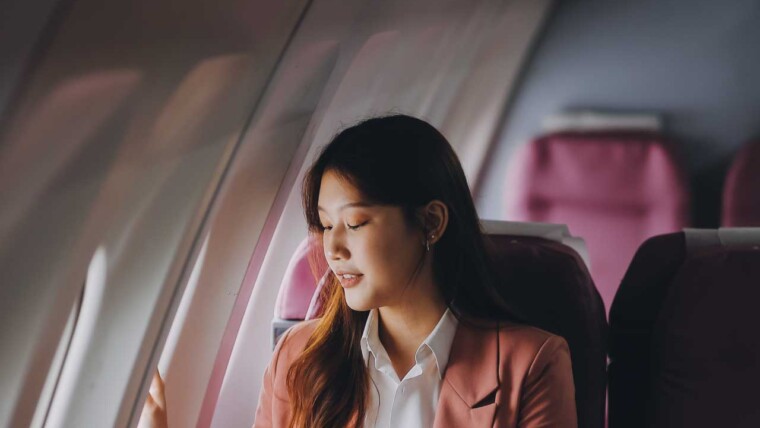 A passenger experiencing comfortable long-haul flights with a travel pillow and blanket, demonstrating relaxation strategies for long journeys.