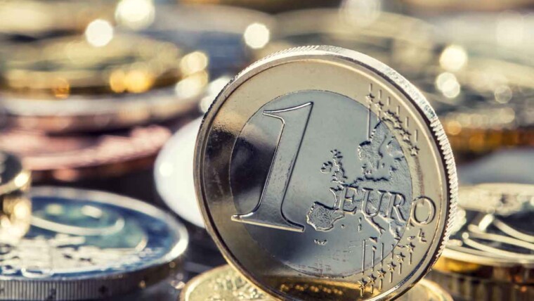 A traveler using a smartphone to check currency exchange rates while holding foreign currency.